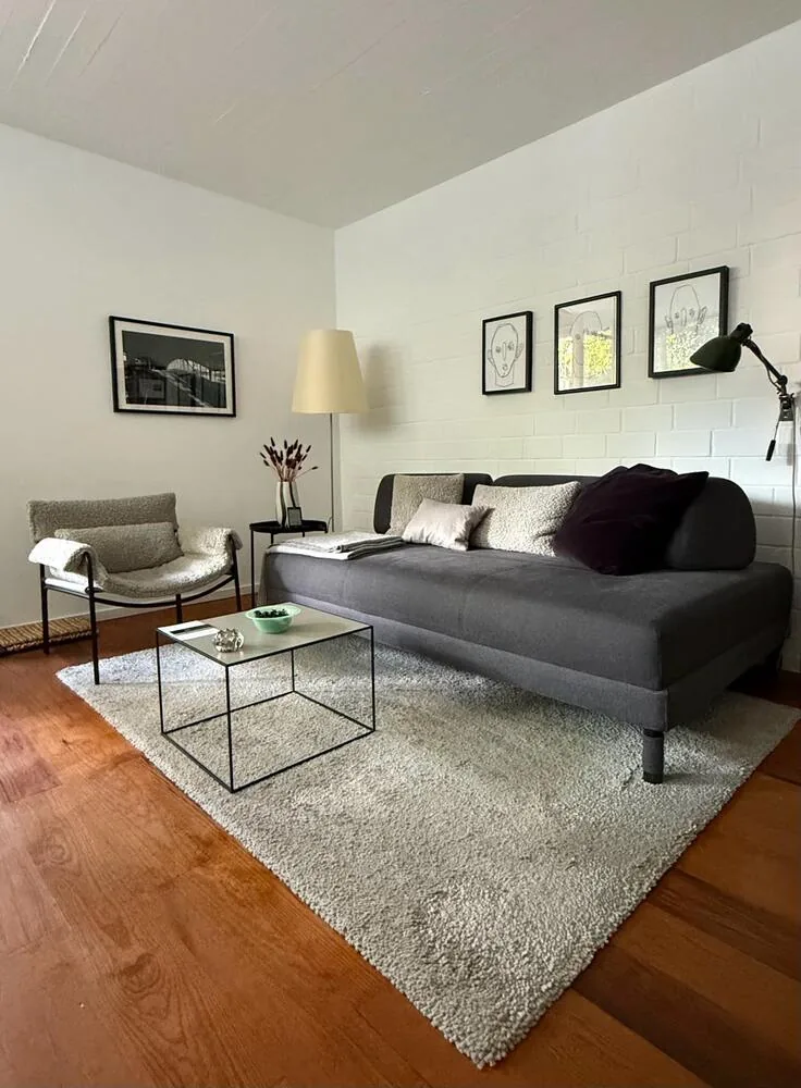 Wohnraum mit Schlafsofa, Sessel und Bildern